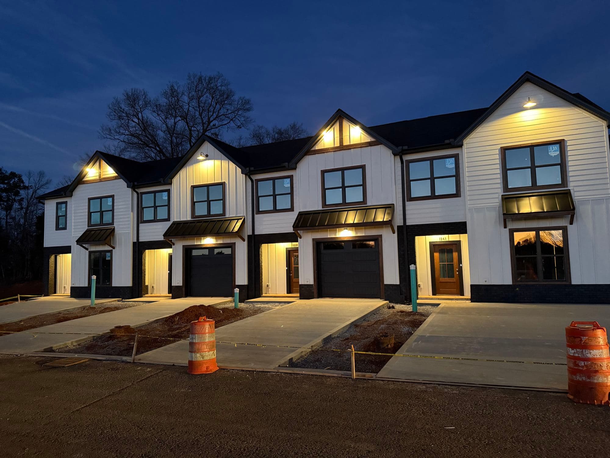 Row of newly built townhomes with warm exterior lighting at dusk